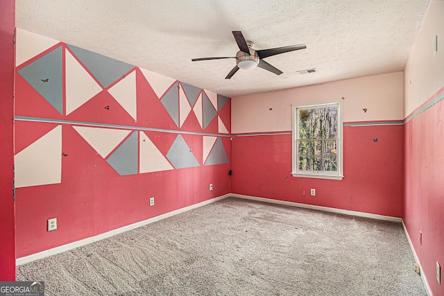 empty room with carpet floors, visible vents, a ceiling fan, a textured ceiling, and baseboards