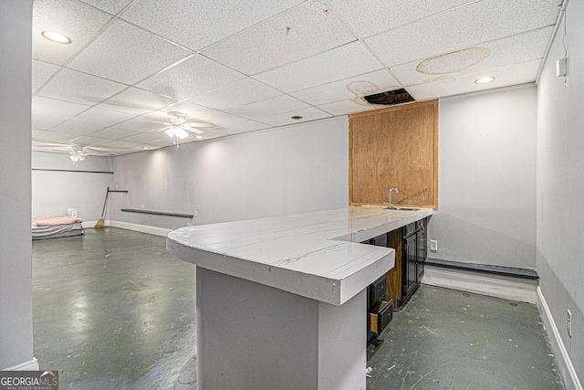 bar with finished concrete flooring, a sink, a paneled ceiling, and baseboards