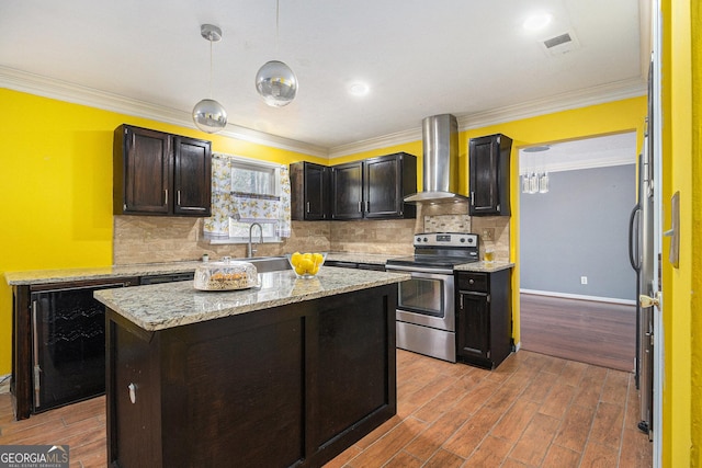 kitchen with visible vents, electric stove, wall chimney exhaust hood, a center island, and decorative light fixtures