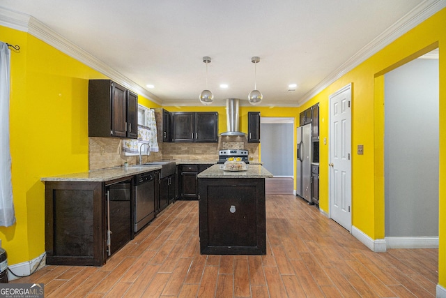 kitchen featuring appliances with stainless steel finishes, light stone counters, decorative light fixtures, a center island, and wall chimney range hood