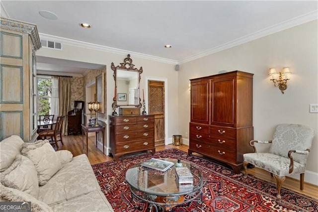 interior space featuring baseboards, wood finished floors, visible vents, and crown molding