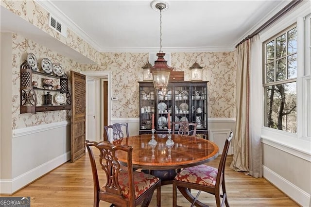 dining space featuring a wainscoted wall, light wood-style floors, and wallpapered walls