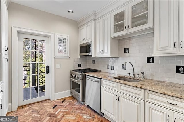 kitchen featuring light stone countertops, white cabinetry, stainless steel appliances, and a sink