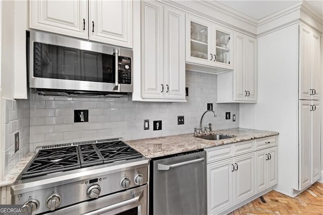 kitchen featuring light stone counters, stainless steel appliances, glass insert cabinets, white cabinetry, and a sink