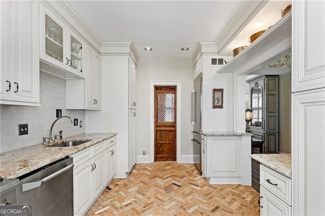 kitchen with light stone counters, stainless steel appliances, a sink, white cabinetry, and glass insert cabinets