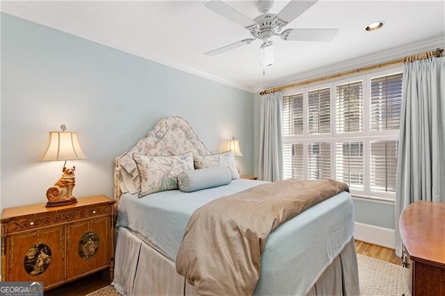 bedroom with baseboards, ceiling fan, wood finished floors, and crown molding