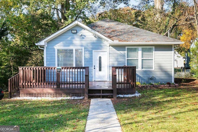 bungalow-style home with a front lawn and a deck