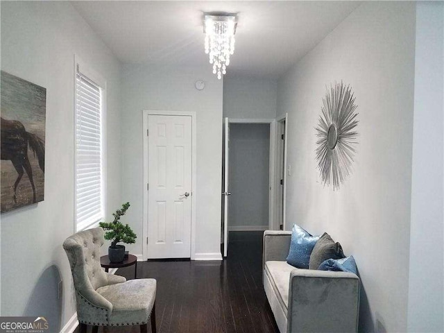 sitting room with an inviting chandelier, dark wood finished floors, and baseboards