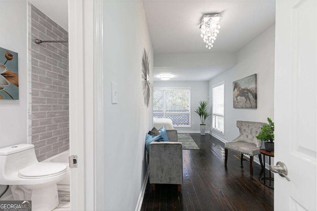 interior space with toilet, baseboards, wood finished floors, and tiled shower