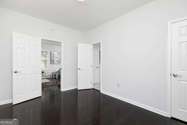 unfurnished bedroom featuring baseboards and dark wood finished floors