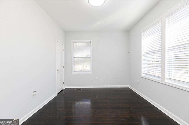 unfurnished room featuring dark wood-style floors, plenty of natural light, and baseboards