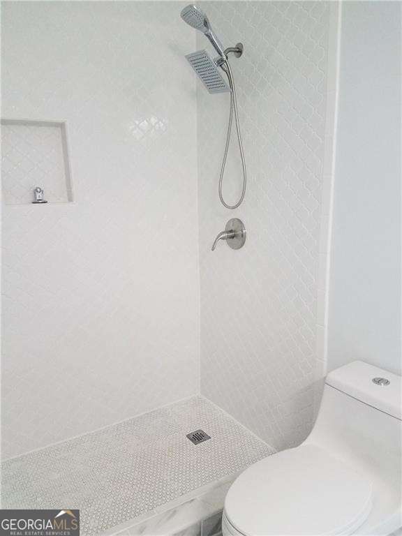 bathroom featuring toilet and a tile shower