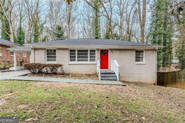 ranch-style home featuring brick siding, a front lawn, and fence