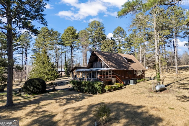 view of home's exterior with a sunroom, a yard, and central AC unit