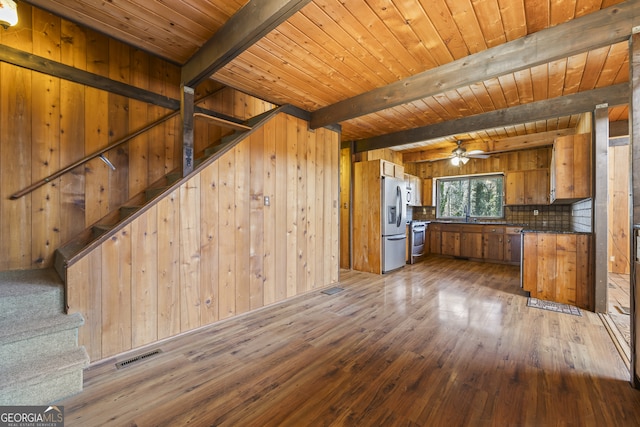 kitchen featuring visible vents, appliances with stainless steel finishes, brown cabinets, dark wood-type flooring, and wood walls