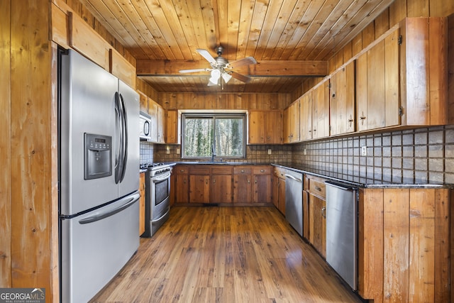 kitchen featuring a sink, appliances with stainless steel finishes, decorative backsplash, dark countertops, and dark wood finished floors