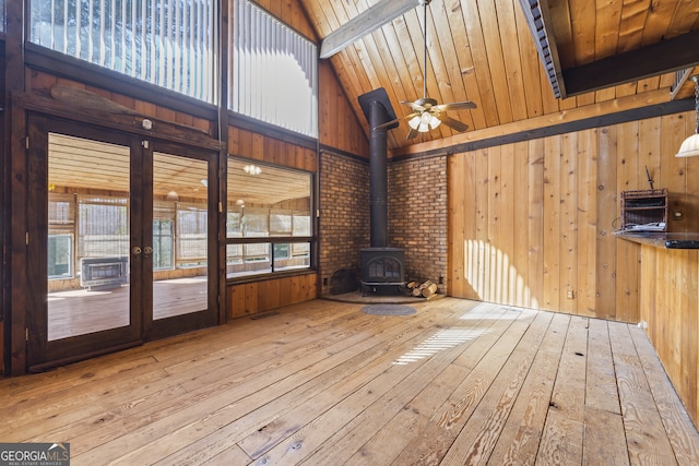 interior space featuring visible vents, lofted ceiling with beams, a wood stove, ceiling fan, and wooden ceiling