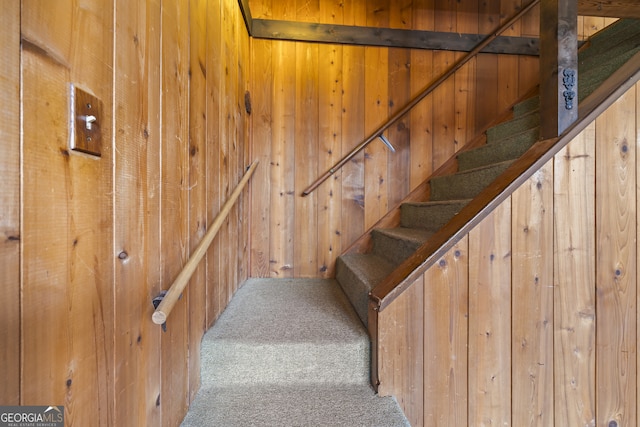 staircase with carpet and wooden walls