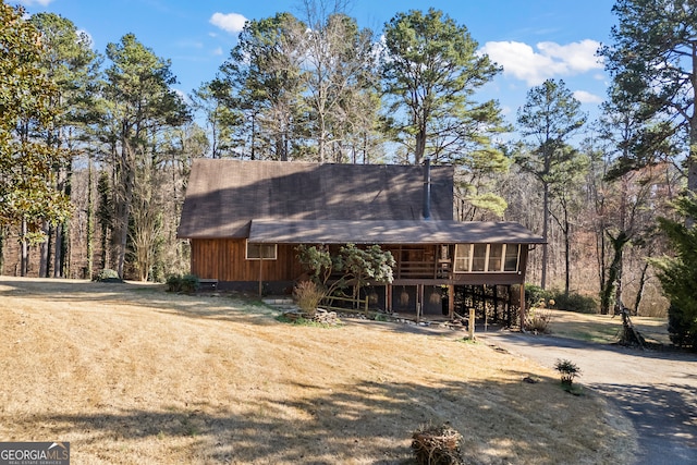 view of front of home with a carport, a front yard, a sunroom, and dirt driveway