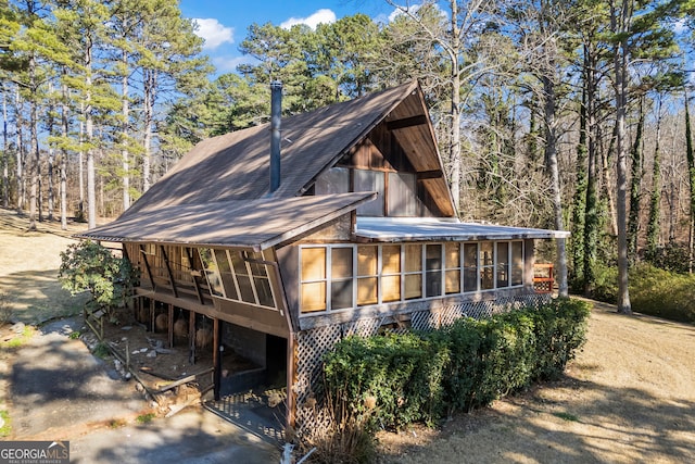 view of home's exterior with roof with shingles and a sunroom