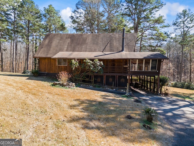 view of front of home with driveway, a front lawn, and a sunroom