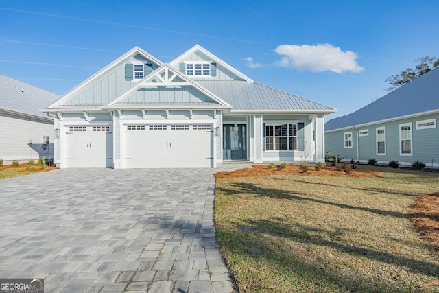 view of front of property with an attached garage, decorative driveway, a front lawn, and board and batten siding