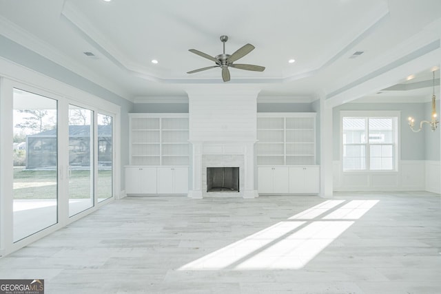 unfurnished living room with a healthy amount of sunlight, a fireplace, a raised ceiling, and crown molding