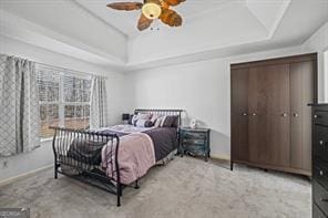 bedroom with baseboards, a raised ceiling, and carpet