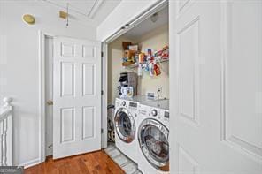 clothes washing area featuring washing machine and clothes dryer, laundry area, attic access, and wood finished floors