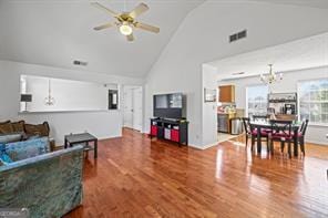 living room with visible vents, high vaulted ceiling, wood finished floors, and ceiling fan with notable chandelier