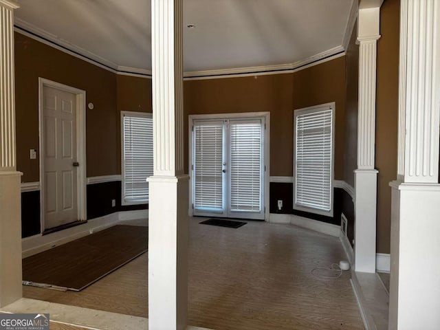 interior space featuring ornate columns, light wood-style flooring, baseboards, and crown molding