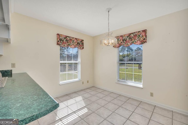 dining space with a chandelier, light tile patterned flooring, and baseboards