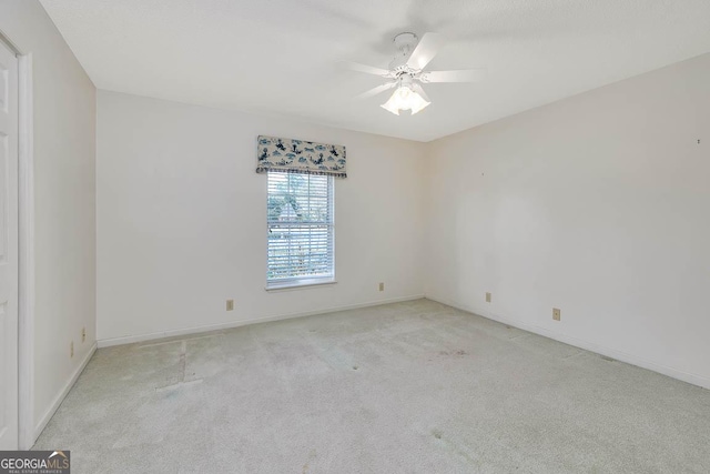 empty room featuring light carpet, ceiling fan, and baseboards