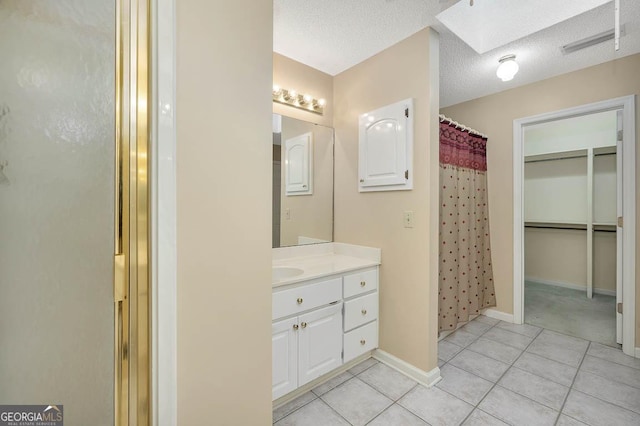 full bath featuring a skylight, visible vents, a stall shower, a textured ceiling, and tile patterned floors