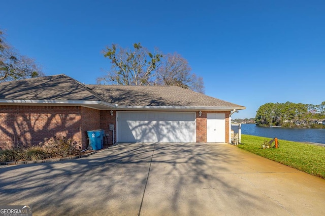 view of front facade featuring an attached garage, driveway, brick siding, and a water view