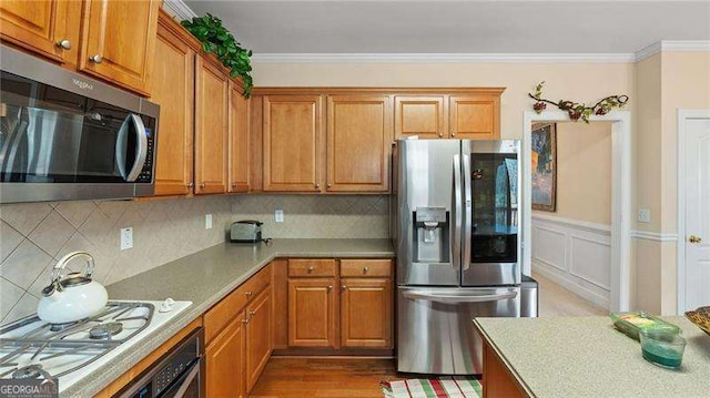 1657 Stilesboro Ridge Dr, Kennesaw, GA 30152 - kitchen with appliances with stainless steel finishes, brown cabinets, ornamental molding, tasteful backsplash, and light countertops