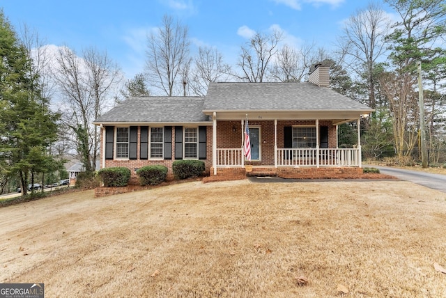 ranch-style home featuring a porch, a front yard, brick siding, and a chimney