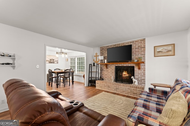 living room with a fireplace, light wood-style flooring, and a notable chandelier