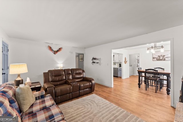 living area with light wood-style flooring, baseboards, and an inviting chandelier