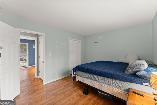 bedroom featuring light wood-type flooring, baseboards, and a closet