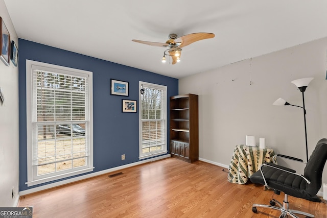 office space featuring light wood-style floors, visible vents, ceiling fan, and baseboards