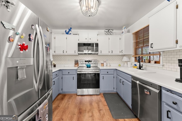 kitchen with stainless steel appliances, light countertops, gray cabinetry, white cabinetry, and a sink