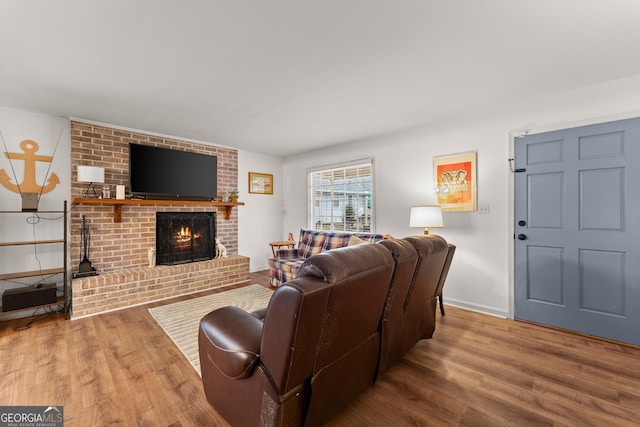 living area featuring a brick fireplace, baseboards, and wood finished floors