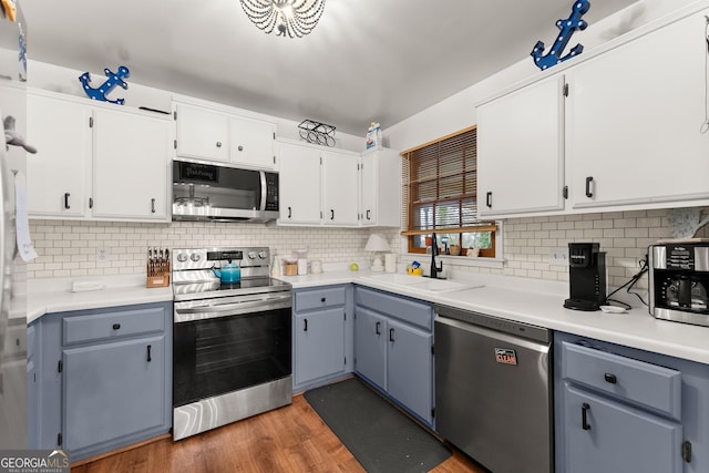 kitchen featuring dark wood-style flooring, a sink, white cabinetry, light countertops, and appliances with stainless steel finishes