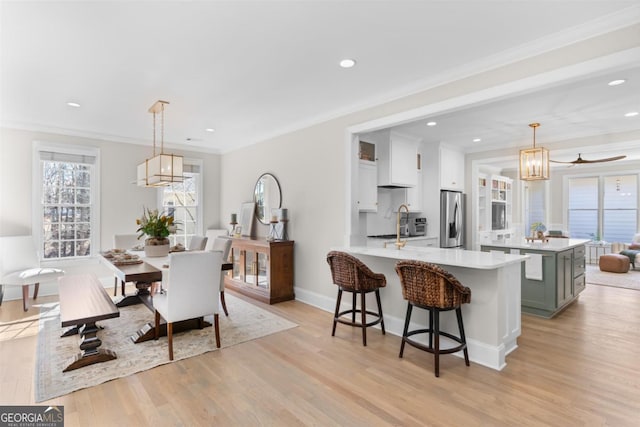 dining room with crown molding, recessed lighting, baseboards, and light wood-style floors