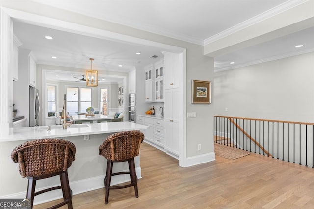 kitchen with stainless steel appliances, light countertops, glass insert cabinets, white cabinetry, and a kitchen breakfast bar