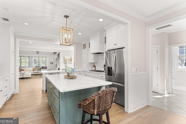 kitchen with visible vents, a kitchen island, appliances with stainless steel finishes, hanging light fixtures, and white cabinetry