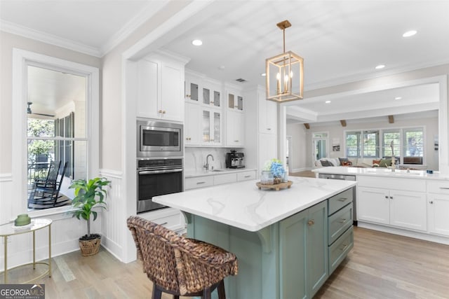 kitchen with glass insert cabinets, a center island, light stone countertops, stainless steel appliances, and white cabinetry