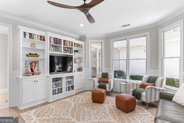 living area with visible vents, ornamental molding, light wood-type flooring, and a wealth of natural light