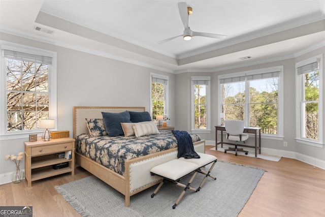 bedroom with crown molding, visible vents, a raised ceiling, and wood finished floors